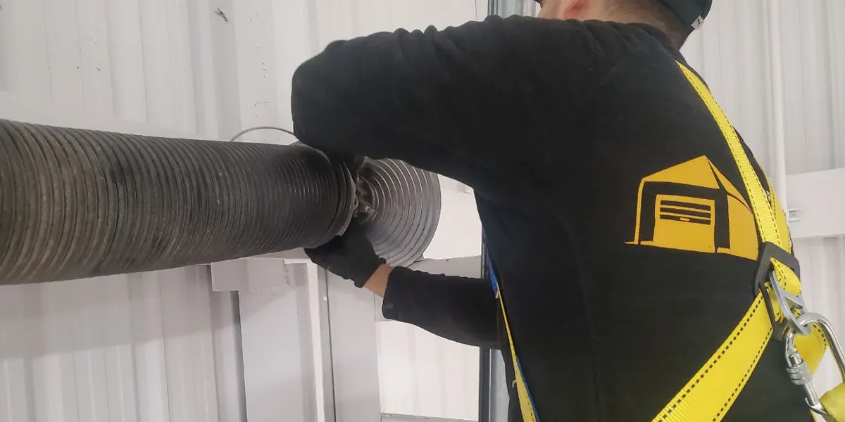 a technician from Unique Garage Door checking on garage door spring for maintenance services in Terrebonne