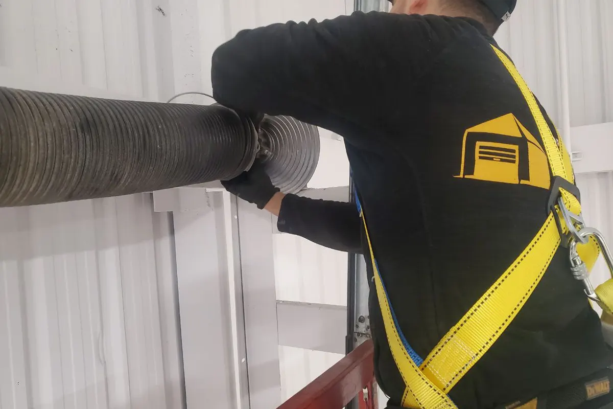 a technician from Unique Garage Door checking the spring for a garage door maintenance