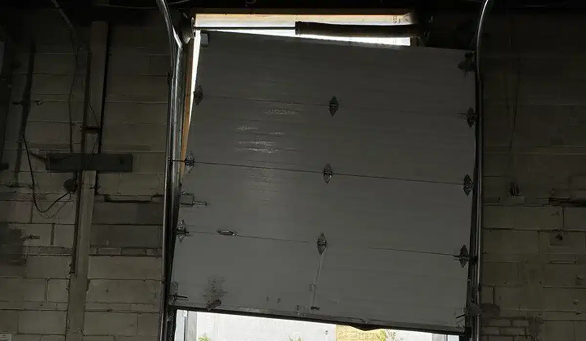 Unique Garage Door Technician repairing a misaligned garage door panel in Dorval