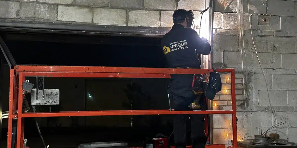 A technician from Unique Garage Door is repairing a garage door in Greater Montreal Area